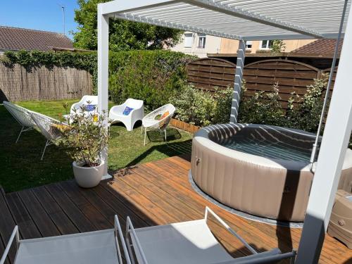 a patio with a hot tub and chairs on a deck at Maison familiale 100m2 in Witry-lès-Reims