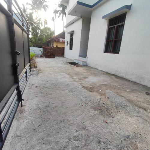 an empty driveway in front of a white house at Ebenezer Stay in Trivandrum