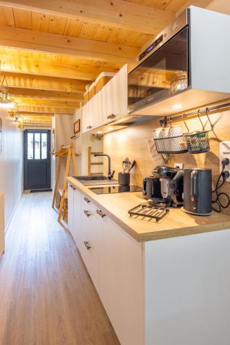 Il comprend une cuisine avec des placards blancs et des plafonds en bois. dans l'établissement La p’tite barque de Saint-Malo, à Saint-Malo