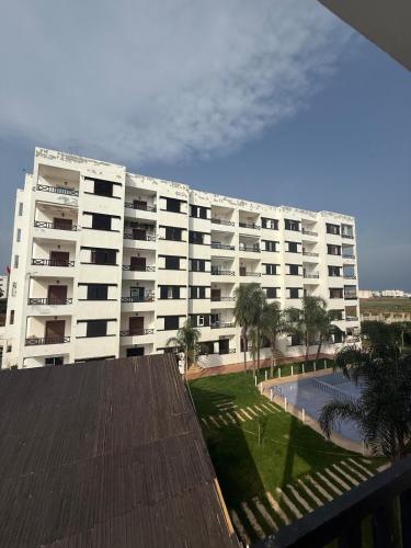 a large white apartment building with a pool in front of it at apartment in complex city center in Oued Laou