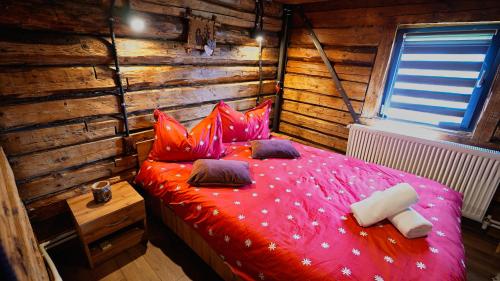 a bedroom with a red bed in a wooden room at Coliba la Valle in Petroşani