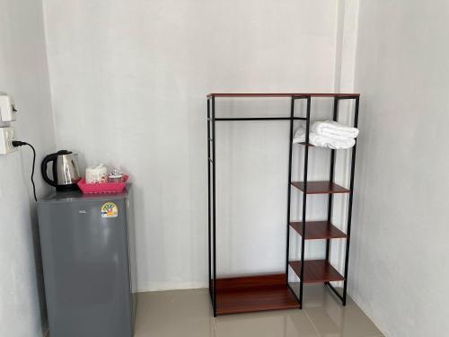 a shelf next to a refrigerator in a room at Saintjirahotel in Ban Nong Chaeng