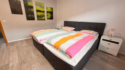 a bedroom with a large bed with colorful sheets at Pension Central Ferienwohnungen in Bad Endbach