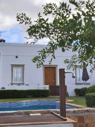 una casa blanca con una piscina delante de ella en Cosy Country House, en Cerro da Cova