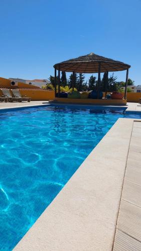 a swimming pool with a gazebo and blue water at Casinha da Galé in Galé
