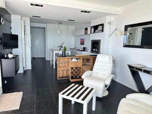 Il comprend un salon avec des chaises blanches et une cuisine. dans l'établissement Magnifique Penthouse Pornichet, à Pornichet