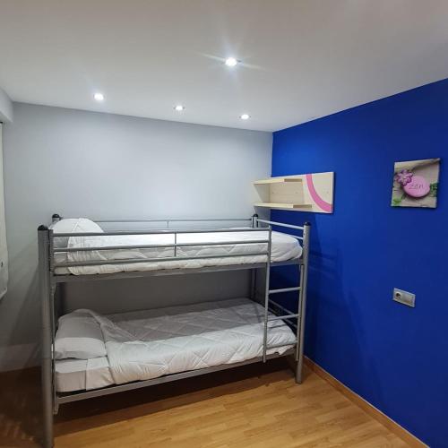 a room with two bunk beds and a blue wall at Nules Beach Apartment in Moncófar