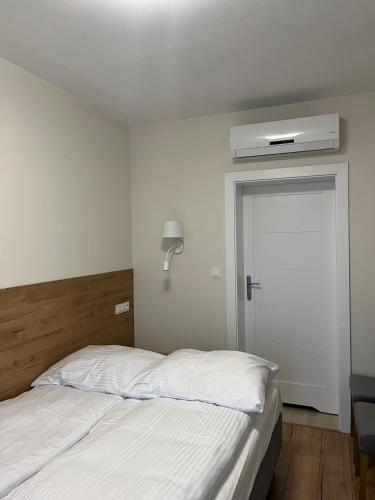 a bedroom with a white bed and a air conditioner at Morskie Oko Apartamenty in Ustronie Morskie