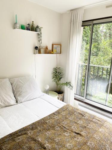 une chambre avec un lit et une grande fenêtre dans l'établissement Havre de paix en plein Paris, à Paris