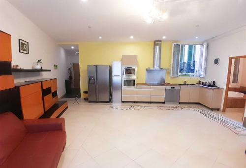 une grande cuisine avec des murs jaunes et des appareils en acier inoxydable dans l'établissement Super CENTRAL NICE, à Nice