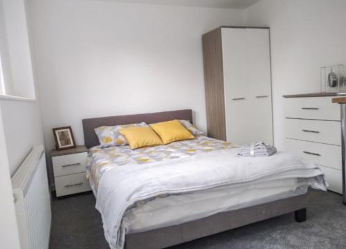 a bedroom with a bed with yellow pillows and a dresser at City breaks Corby Double ensuites with tv in Rockingham