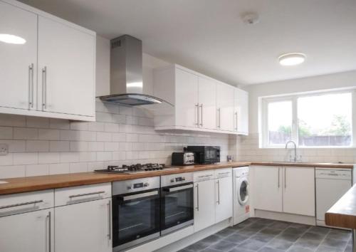 a kitchen with white cabinets and a stove top oven at City breaks Corby Double ensuites with tv in Rockingham