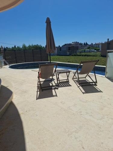 two chairs and an umbrella next to a pool at Apartments Melisa in Ulcinj