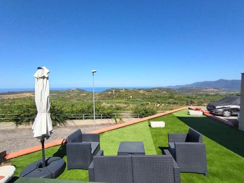 a lawn with chairs and an umbrella and a car at Cas'Aurora in Tresnuraghes