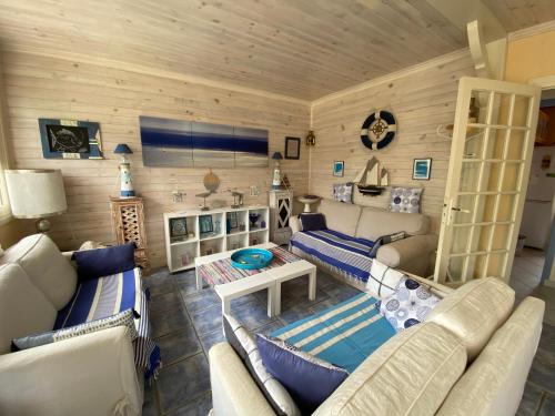 Il comprend un salon doté d'un mobilier blanc et de murs en bois. dans l'établissement Villa CAPBRETON 5 personnes, à Capbreton