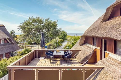 a deck with a table and chairs and an umbrella at Haus Windhook in Dierhagen