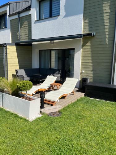 a group of white lounge chairs on a patio at Sea Green House in Monciškės