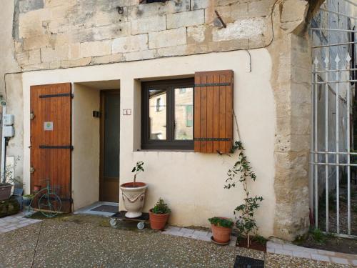un bâtiment avec une porte, une fenêtre et des plantes en pot dans l'établissement les greniers du château, à Aramon