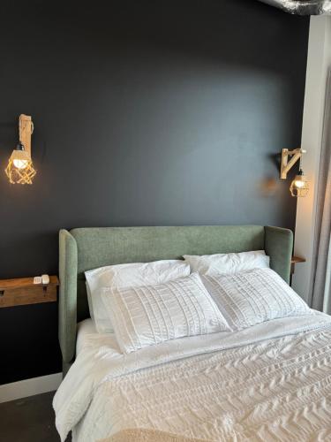 a bed with a green headboard and white sheets at Stylish Condo, Riverview, Downtown East Village, Mins to Stampede, Saddledome in Calgary