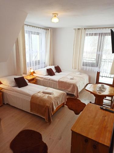 a bedroom with two beds and a table and windows at Stramówka in Groń