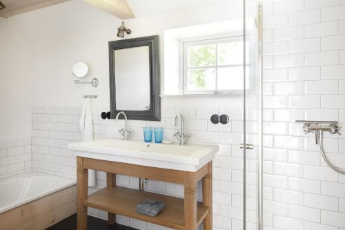 a white bathroom with a sink and a shower at Urgemütliche Reetdachkate mit großem Kamin und Sauna in Pommerby