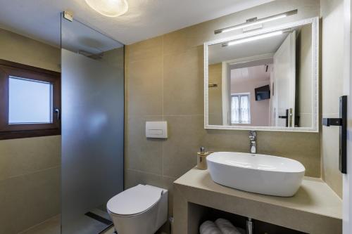 a bathroom with a sink and a toilet and a mirror at Bleu & Vert in Skopelos Town