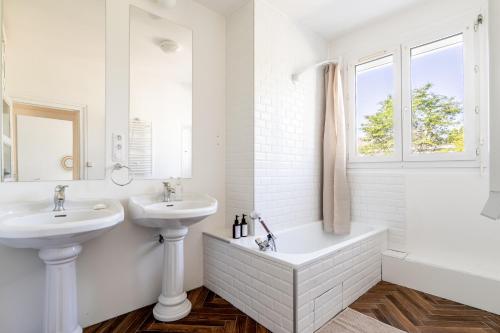 a white bathroom with two sinks and a bath tub at Appartement T4 centre-ville St Nazaire in Saint-Nazaire
