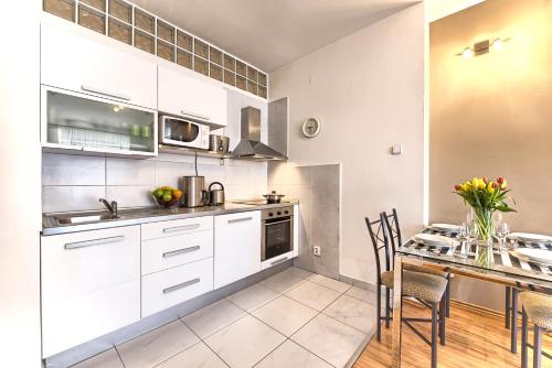プラハにあるOstrovni 7 Apartmentsのキッチン(白いキャビネット、テーブル、椅子付)