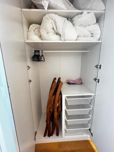 a walk in closet with white shelves and wooden chairs at 4 mins walk Thalwil Station, Free Parking, Historical in Thalwil