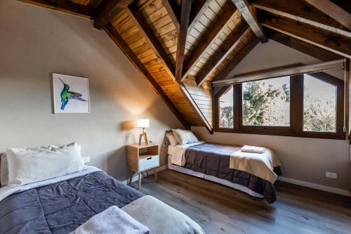 Un dormitorio abuhardillado con dos camas y una ventana. en CIERVO - Departamento céntrico, en Villa La Angostura