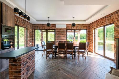 a dining room with a brick wall and a table and chairs at Galuonų vilos in Inturkė