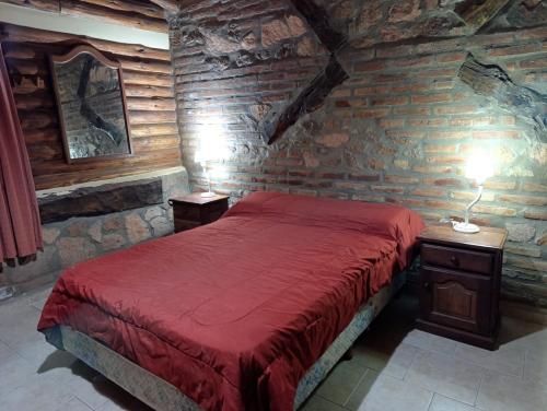 una camera con un letto rosso in una parete in pietra di Cabañas Postal de la Villa a Villa Carlos Paz
