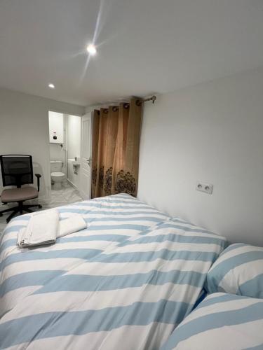 a bedroom with a blue and white striped bed at Chambre dans un appartement in Ormesson-sur-Marne