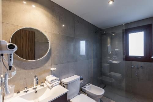 Un baño con lavabo, inodoro y espejo. en CIERVO - Departamento céntrico, en Villa La Angostura