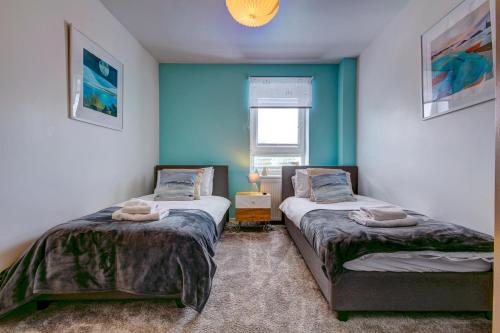 two beds in a room with blue walls at River Ayr View-Coorie Doon Stays in Ayr
