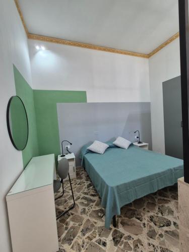 a bedroom with a green bed and a mirror at A un Passo dal Tramonto in Marsala