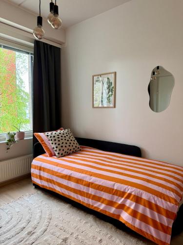a bedroom with a bed with an orange and white striped blanket at Central Studio 33m2 Sauna Wifi Parkkipaikka in Kuusamo
