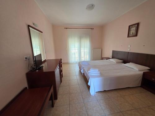 a bedroom with a large white bed and a television at Studio Filippos in Possidi