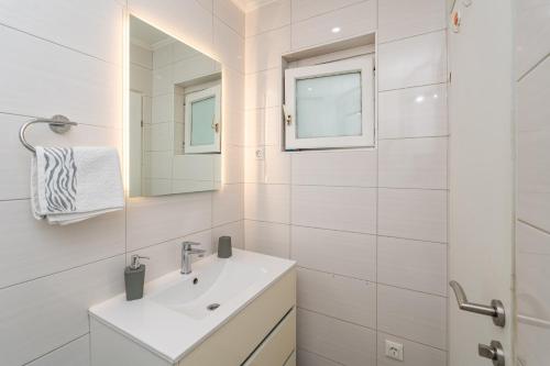 Un baño blanco con lavabo y espejo. en RITA - Charming 2-Bedroom Apartment with sea view, Slano, en Slano