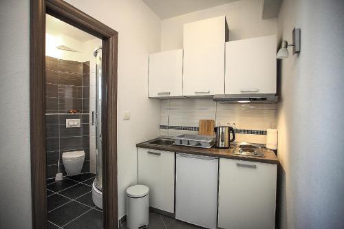 a small kitchen with white cabinets and a toilet at Apartments Nevistic in Podstrana