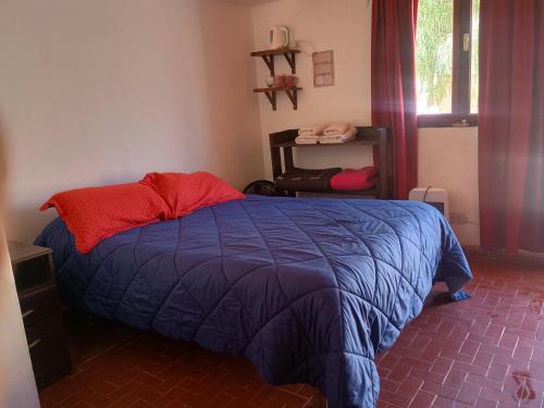 ein Schlafzimmer mit einem blauen Bett mit roten Kissen und einem Fenster in der Unterkunft ElPoro in Purmamarca