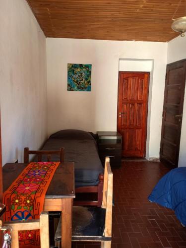 ein Schlafzimmer mit einem Bett und einem Tisch und einer Tür in der Unterkunft ElPoro in Purmamarca