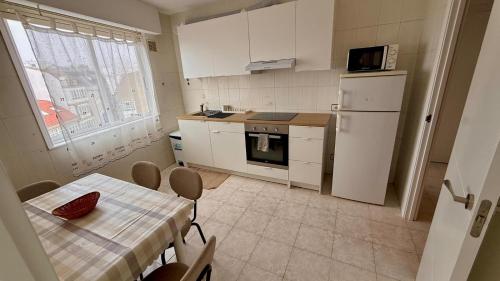 kuchnia ze stołem i białą lodówką w obiekcie Apartamento marinero w mieście Malpica