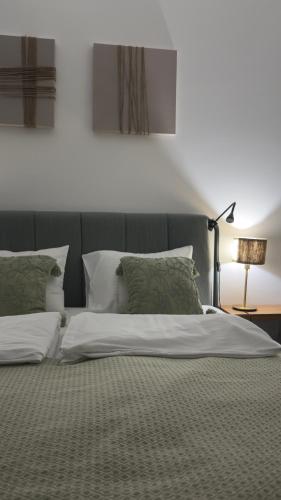 a large bed with white sheets and green pillows at Code3 Srebrno Jezero in Veliko Gradište