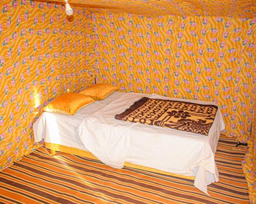 a small bed in a room with a wall at magical saharain camp in Merzouga