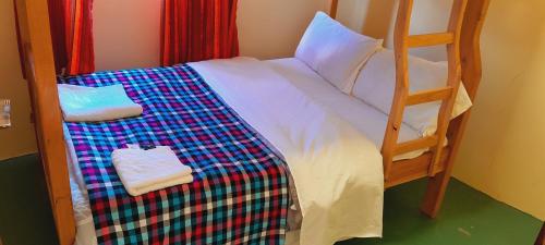 a bunk bed with a checkered blanket and two towels at Manyatta Homestay in Sekenani