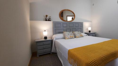a bedroom with a bed with a yellow blanket and a mirror at Casa Saballa in O Grove