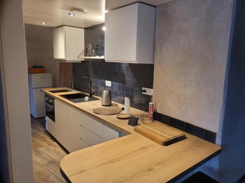eine Küche mit weißen Schränken und einer Arbeitsplatte aus Holz in der Unterkunft Maison troglodyte in Saint-Martin-de-la-Place