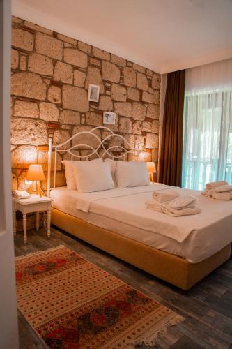 a bedroom with a large bed and a stone wall at Albeon Luxury Hotel - Alacatı in Alaçatı