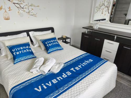 a bed with blue and white blankets and pillows at Vivenda Terinho in Barcelos